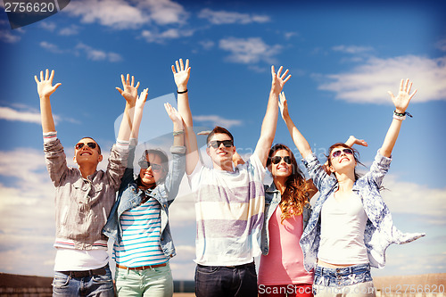 Image of group of smiling teenagers holding hands up