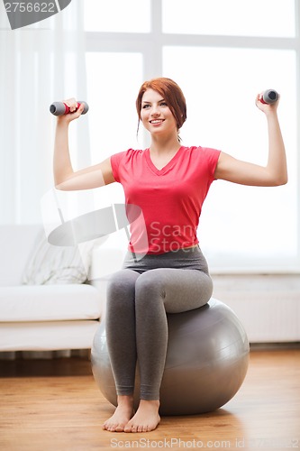 Image of smiling redhead girl exercising with fitness ball