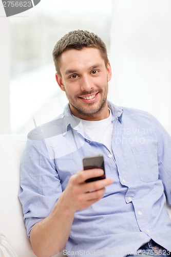 Image of smiling man with smartphone at home