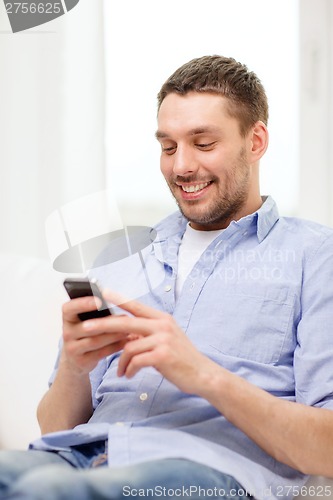 Image of smiling man with smartphone at home