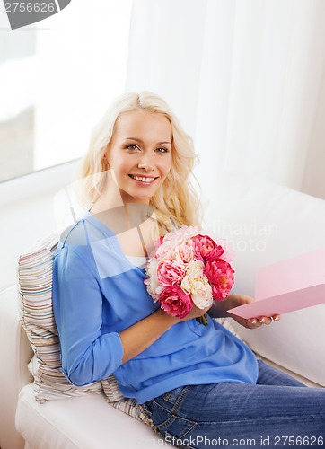 Image of smiling woman with card and bouquet of flowers