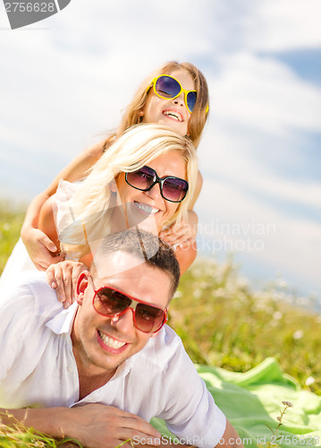 Image of smiling family in sunglasses lying on blanket