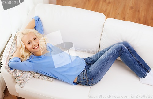 Image of smiling young woman lying on sofa at home