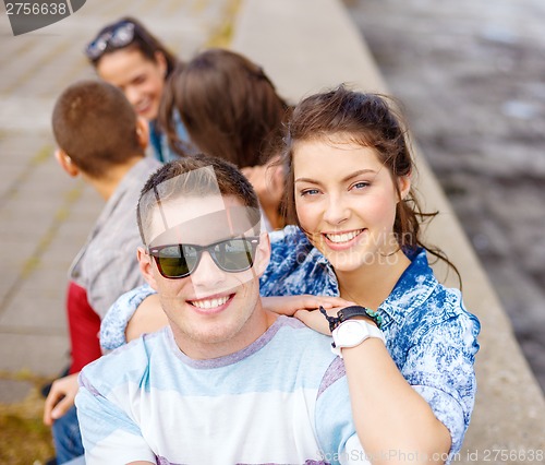 Image of smiling teenagers in sunglasses having fun outside