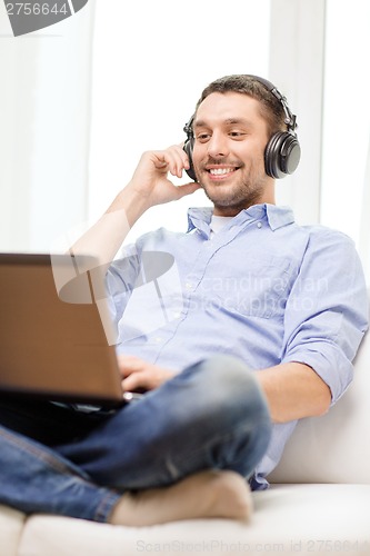 Image of smiling man with laptop and headphones at home
