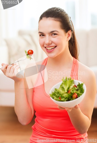 Image of smiling teenage girl with green salad at home