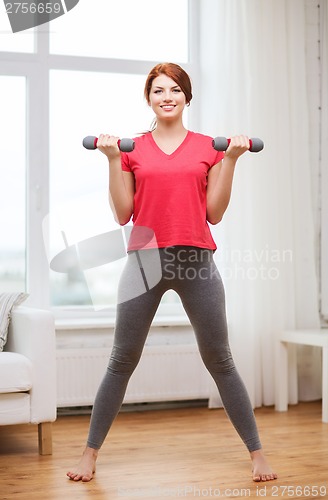 Image of smiling teenage girl exercising with dumbbells