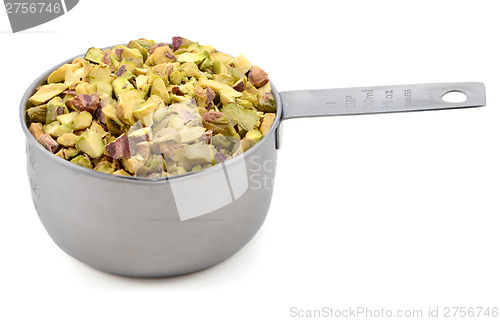 Image of Chopped pistachio nuts in a metal cup measure