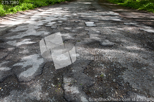 Image of Damaged road full of cracked potholes in pavement