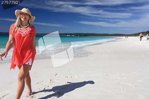 Image of Happy smiling woman walking along beautiful sandy beach