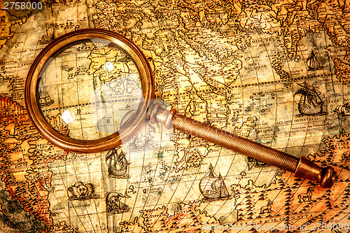 Image of Vintage magnifying glass lies on an ancient world map