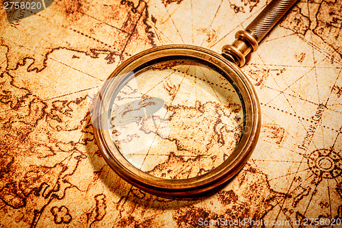 Image of Vintage magnifying glass lies on an ancient world map