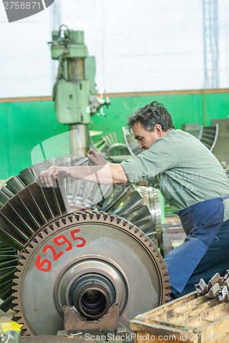 Image of Mechanic assembles turbine for aviation engine