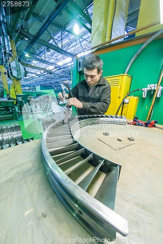 Image of Worker assembles part for aviation engine