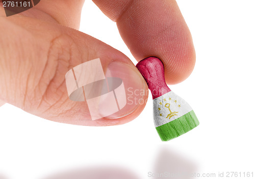 Image of Hand holding wooden pawn, flag painting, selective focus