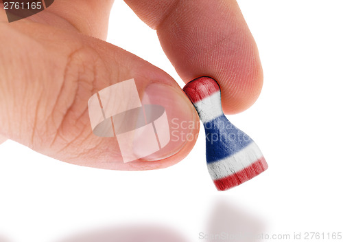 Image of Hand holding wooden pawn, flag painting, selective focus