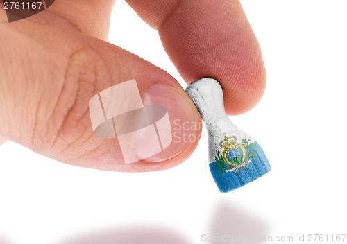 Image of Hand holding wooden pawn, flag painting, selective focus