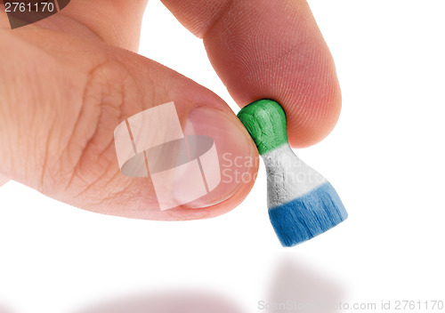 Image of Hand holding wooden pawn, flag painting, selective focus