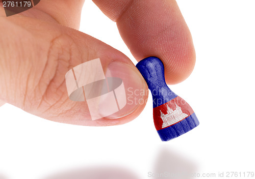 Image of Hand holding wooden pawn, flag painting, selective focus