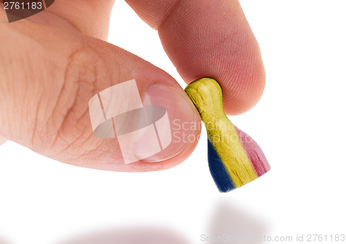 Image of Hand holding wooden pawn, flag painting, selective focus