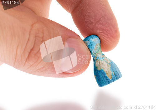 Image of Hand holding wooden pawn, map painting, selective focus