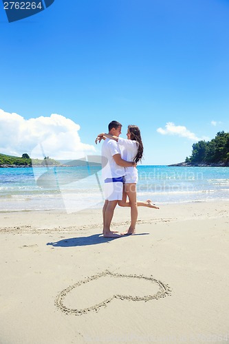 Image of romantic  couple in love  have fun on the beach with heart drawi