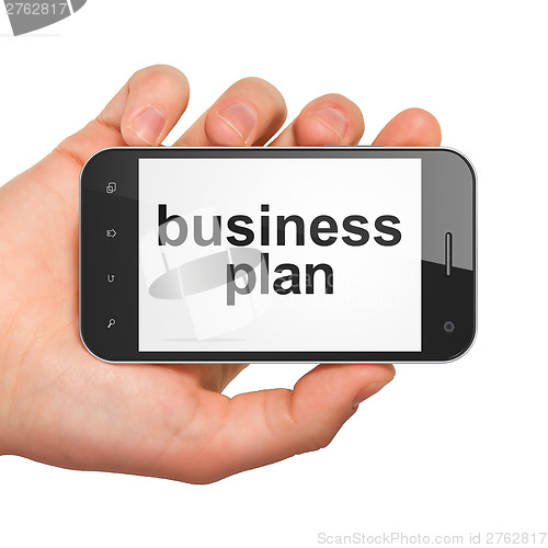 Image of Hand holding smartphone with word business plan on display. Gene