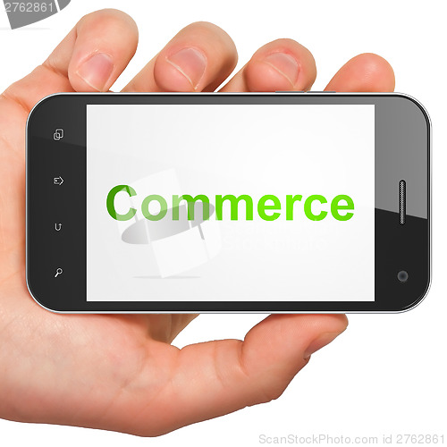 Image of Hand holding smartphone with word Commerce on display. Generic m