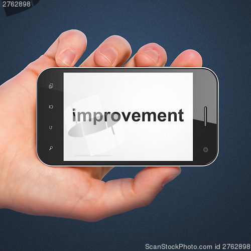 Image of Hand holding smartphone with word improvement on display. Generi