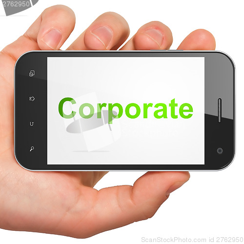 Image of Hand holding smartphone with word Corporate on display. Generic