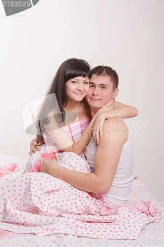 Image of Newlyweds embracing sitting in bed