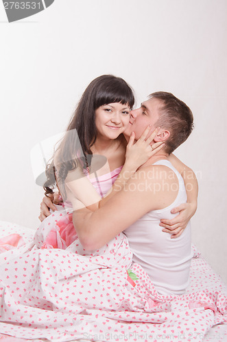 Image of Young boy hugging a beautiful girl in bed