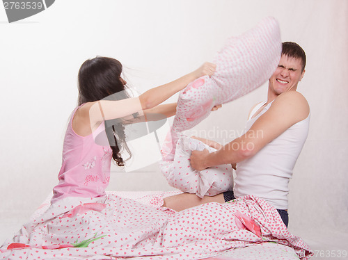 Image of Young couple in bed arranged a pillow fight
