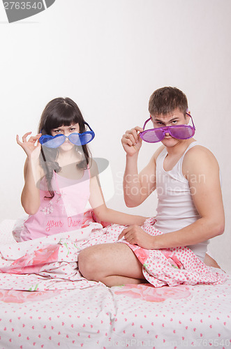 Image of Young couple sitting in bed with big glasses