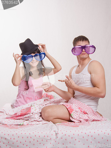 Image of Young couple sitting in bed with big glasses