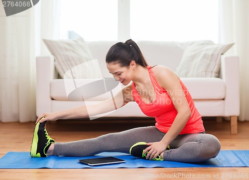 Image of smiling teenage girl streching on floor at home