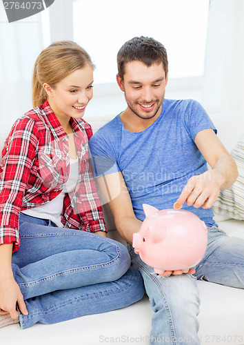 Image of smiling couple with piggybank sitting on sofa