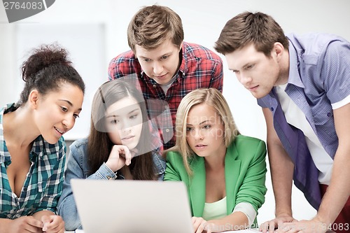 Image of international students looking at laptop at school