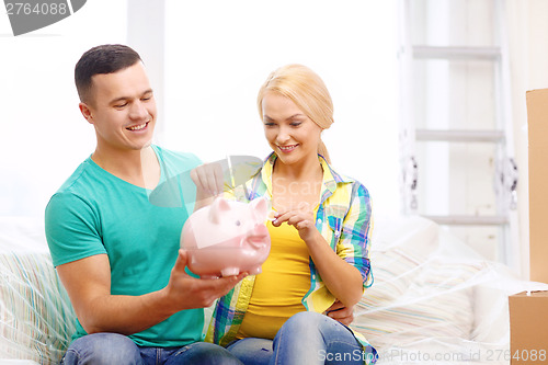 Image of smiling couple with piggybank in new home