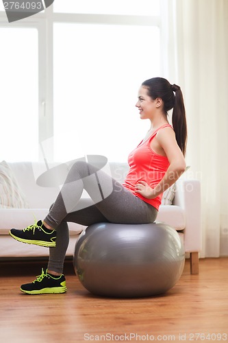 Image of smiling redhead girl exercising with fitness ball