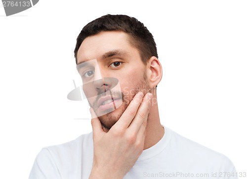 Image of beautiful calm man touching his face