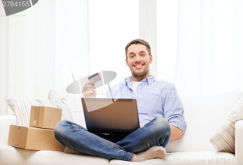 Image of man with laptop, credit card and cardboard boxes