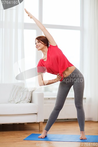 Image of smiling teenage girl streching at home