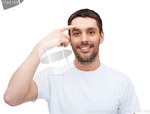 Image of smiling young handsome man pointing to forehead