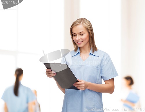 Image of smiling female doctor or nurse with clipboard