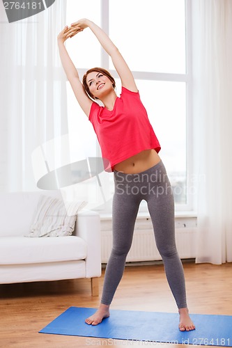 Image of smiling teenage girl streching at home
