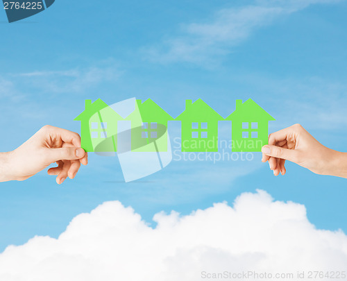 Image of man and woman hands with many green paper houses