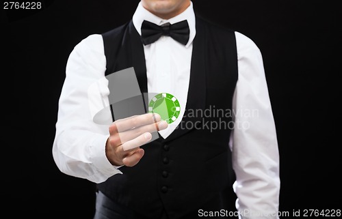 Image of dealer holding green poker chip