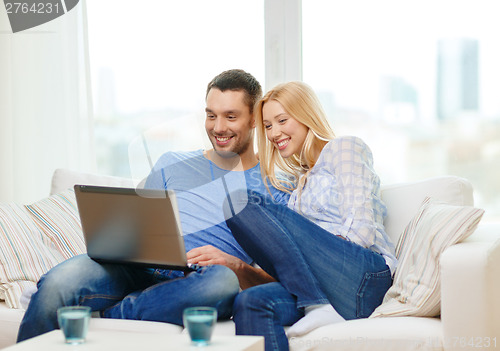 Image of smiling happy couple with laptop at home