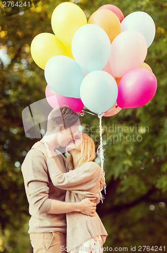 Image of couple with colorful balloons kissing in the park